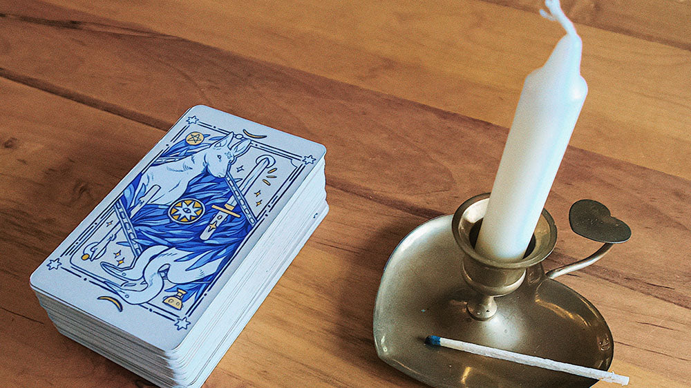 A deck of tarot cards beside a snuffed-out candle with smoke curling up, signifying the conclusion of a New Year's tarot session and the contemplation of revealed insights