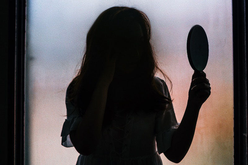 Silhouetted figure with mirror - Identifying Shadow Self Indicators