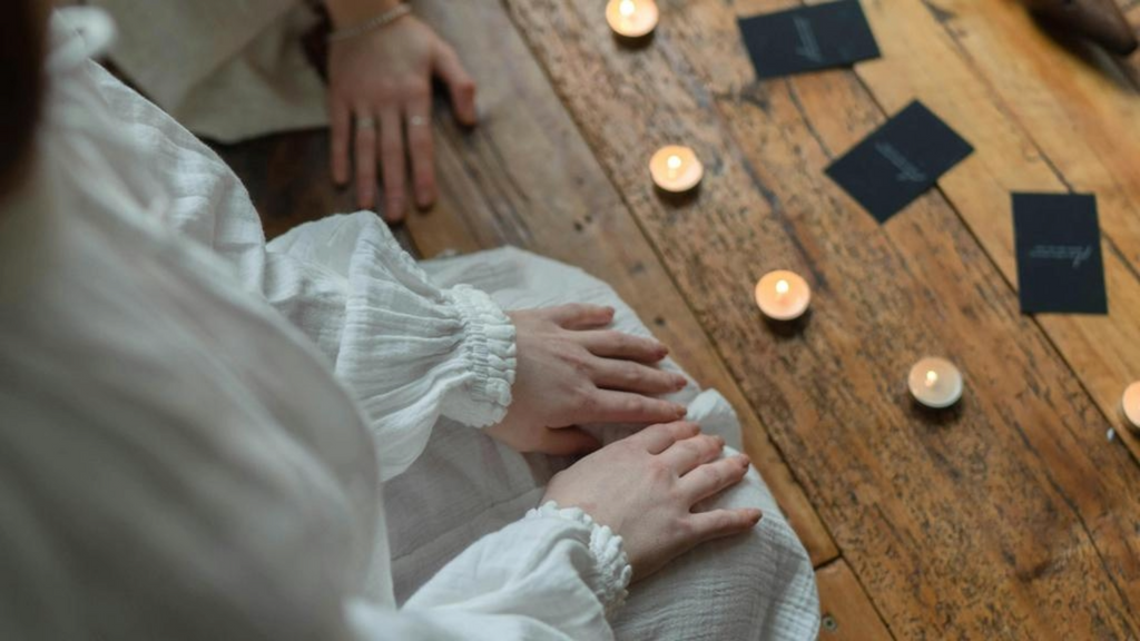 A serene setting with candles and cards laid out on a wooden table, highlighting the reflective and ritualistic aspects associated with the Snow Moon.