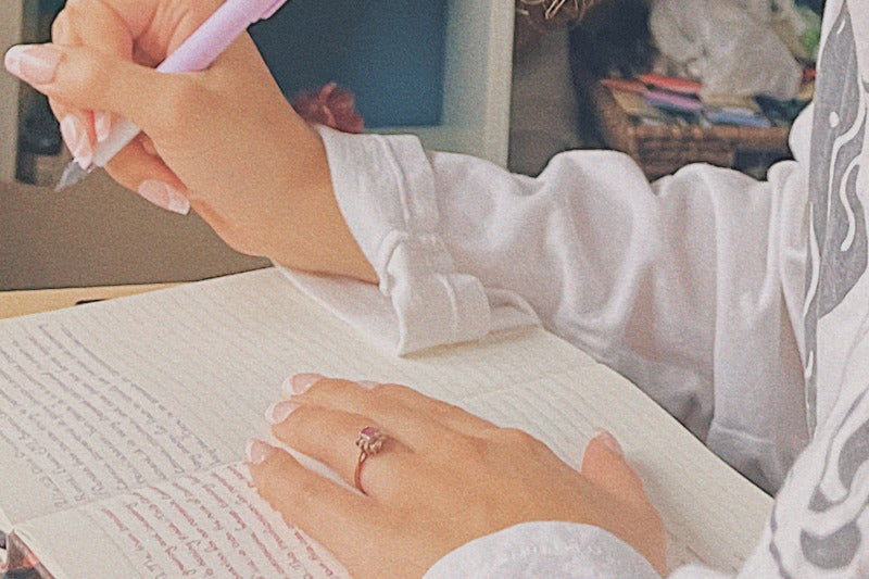 Close-up image of a person journaling during Mercury retrograde, symbolizing self-reflection, planning, and the practice of self-compassion. This dreamy, washed-out photograph embodies the calm and introspective energy needed to navigate retrograde periods effectively.