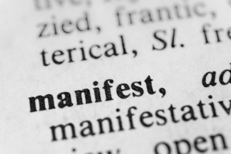 Close-up shot of the dictionary entry for 'manifest', highlighting the importance and meaning of manifestation in the context of personal growth and achievement.