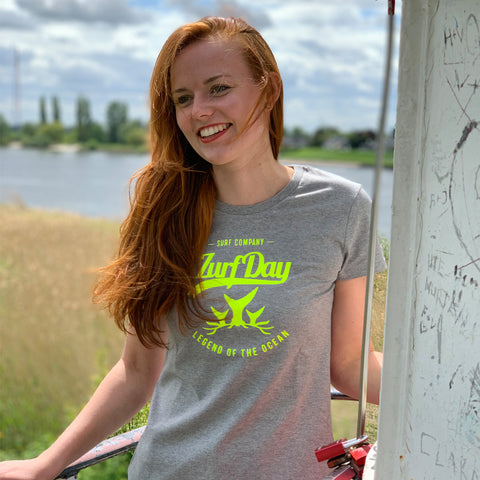 junge Frau steht auf einem Leuchturm, lächelt und trägt ein Zurfday T-Shirt