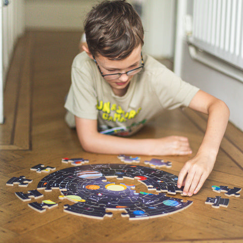 Boy completing wooden Space Explorer floor puzzle