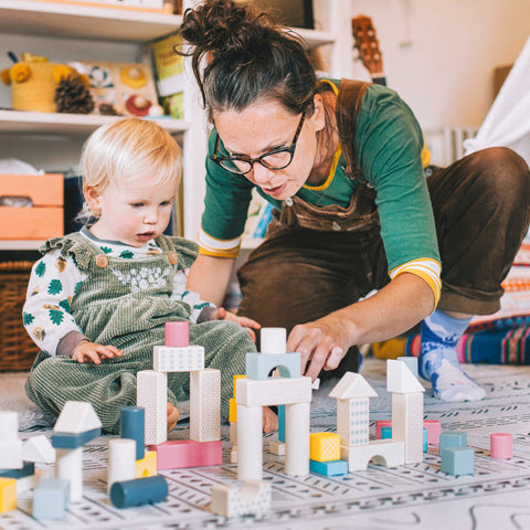 Mum showing daughter how to stack wooden bricks