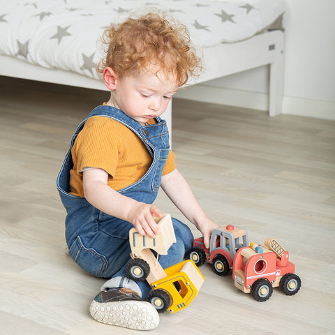 Boy playing with Red Toy Tractor and other mini vehicles
