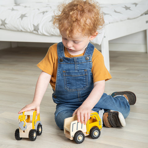 Boy playing with mini wooden construction vehicles