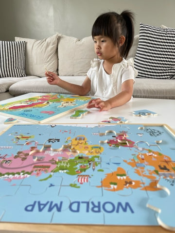 Girl piecing together two wooden map puzzles