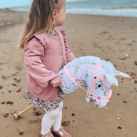 Girl riding Floral Hobby Horse at the beach