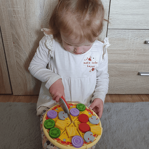 Girl cutting up wooden toy pizza