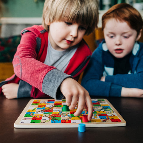 Two friends playing Traditional Snakes & Ladders board game