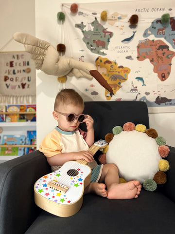 Boy playing with musical Guitar toy in his bedroom