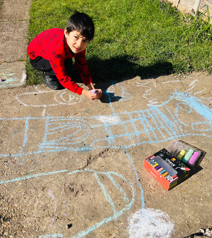 Unplugged play: child drawing outside with pavement chalk