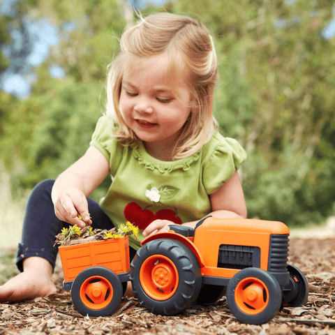 Girl playing with Green Toys Orange Tractor Toy