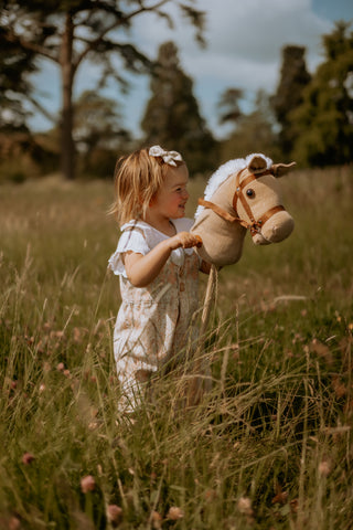 Girl riding Cord Hobby Horse in a summery field