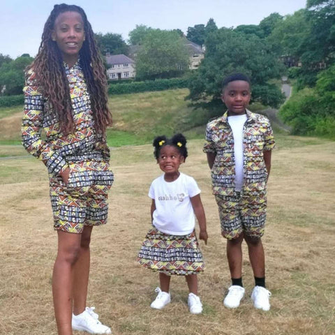 lady with son and daughter wearing matching outfits standing on grass.