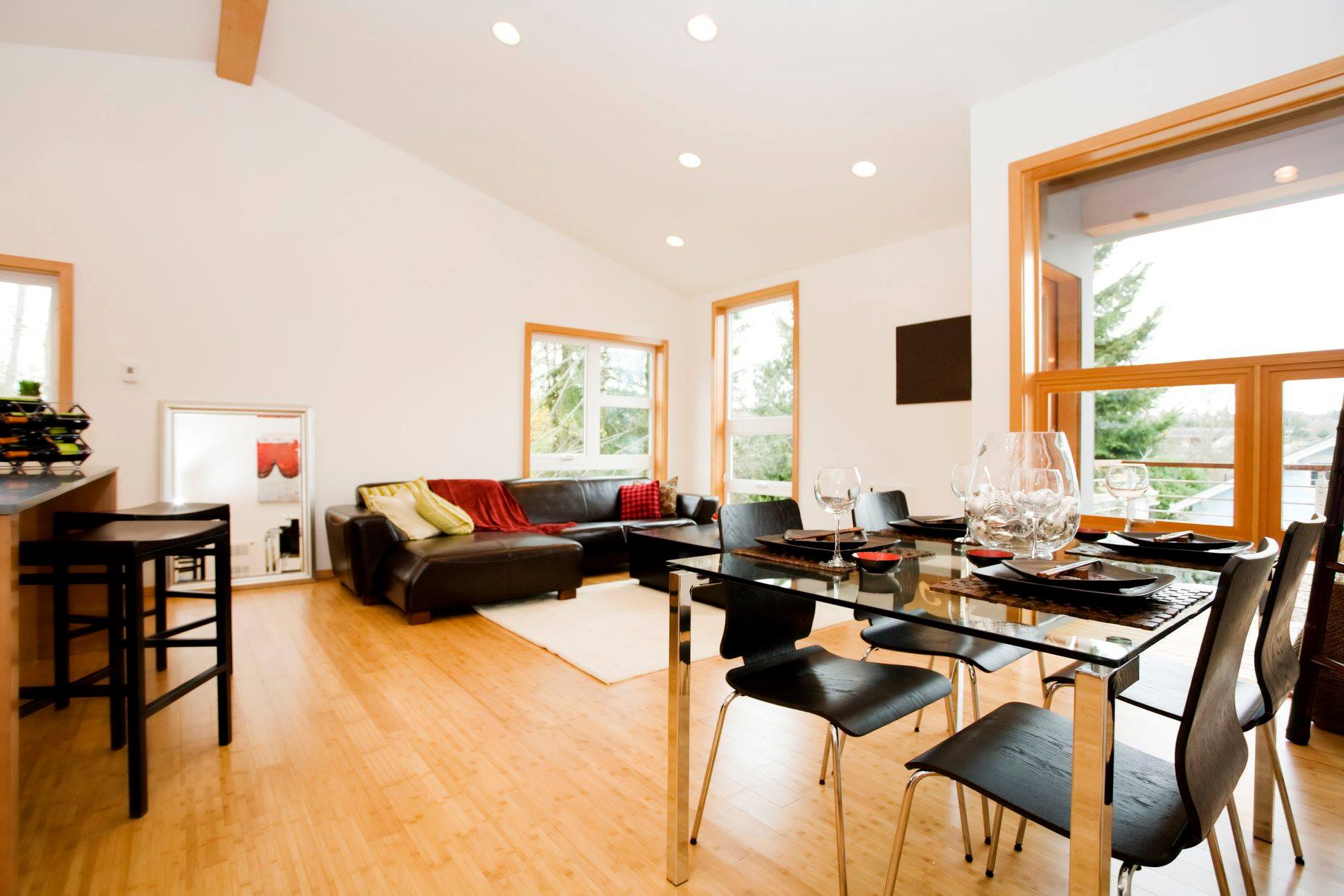 Square clear glass table with flat polish edges and four chairs in an open floor plan