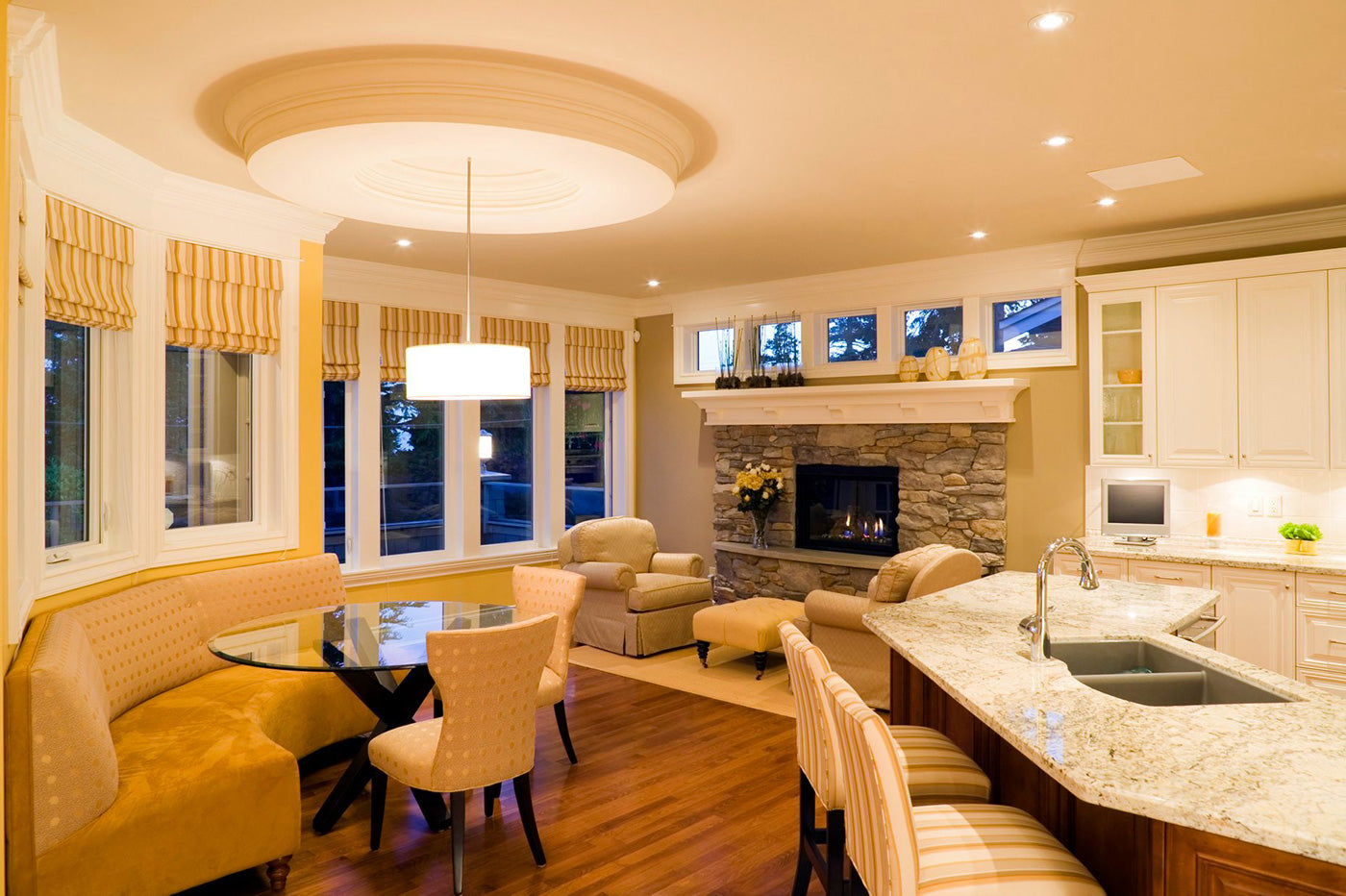 Round clear glass table surrounded by dining set next to kitchen counters and two chairs in front of fireplace in background