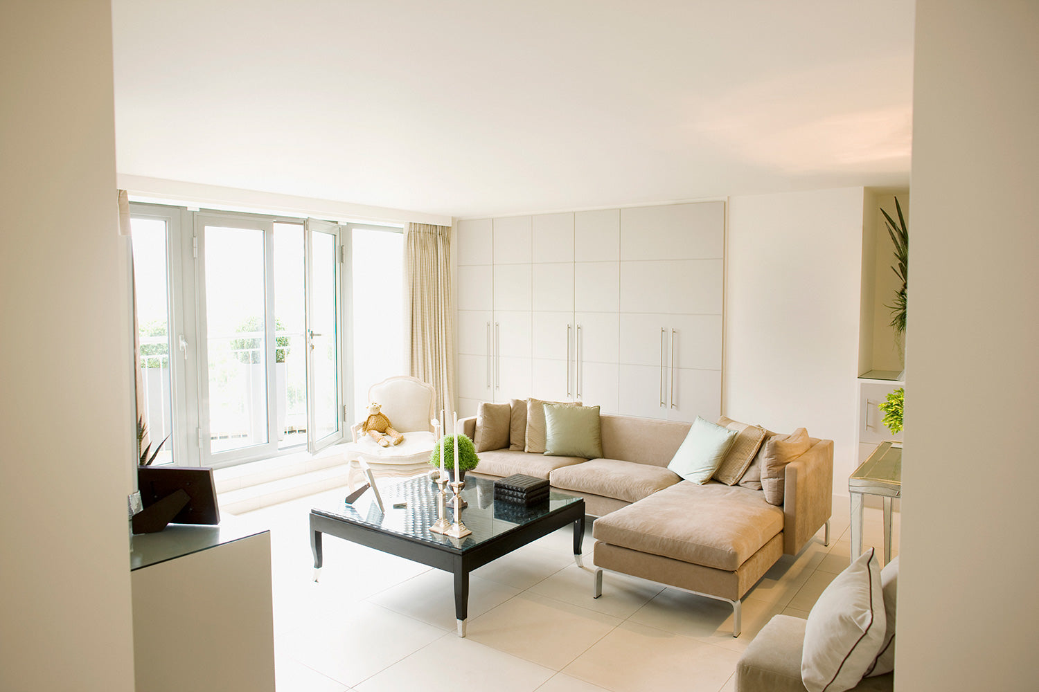 Square clear glass table on a black base in a living area next to a tan sectional