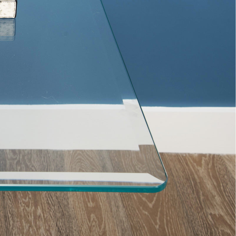 Square glass table corner close up with blue, white, and wood pattern in background