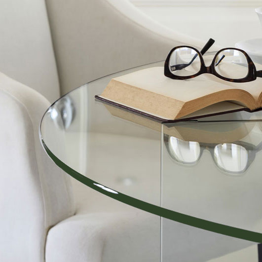 Round clear glass table top showing dark edge with glasses and a book on top