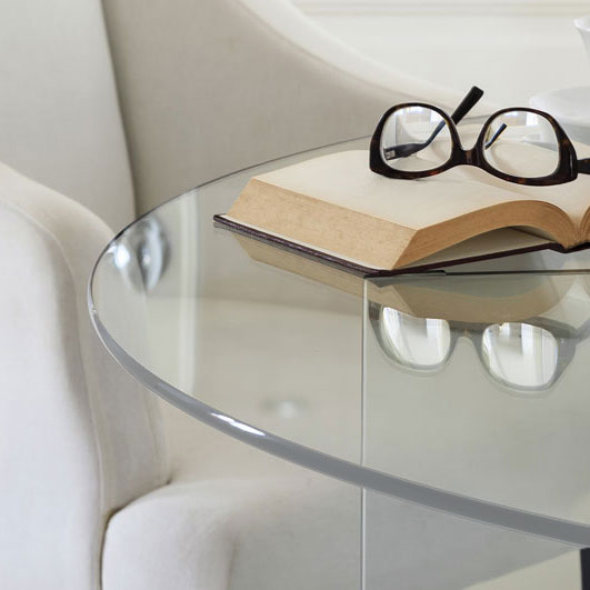 Round clear glass table top showing light edge with glasses and a book on top