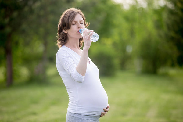 donna incinta che beve in un parco