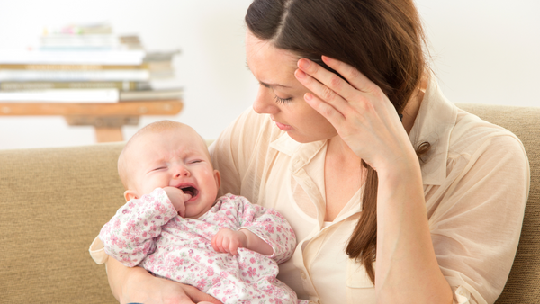 parent struggling to comfort a teething baby in pain and crying
