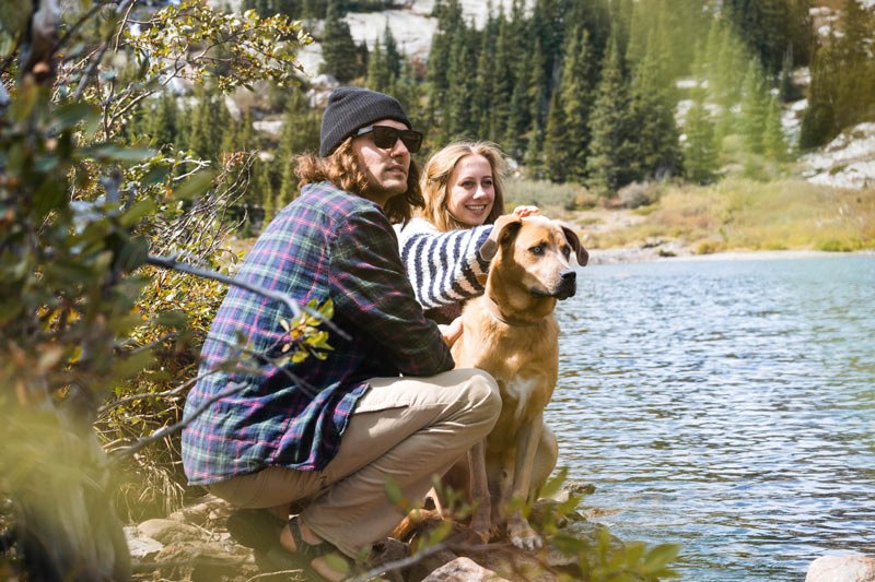 couple hiking with their dog by a lake