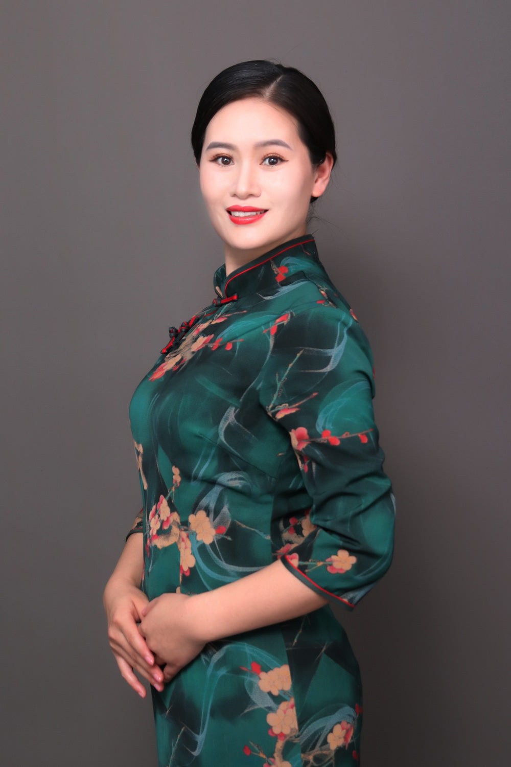 Lynne is wearing a green cheongsam and standing upright for sanuscode advertising use