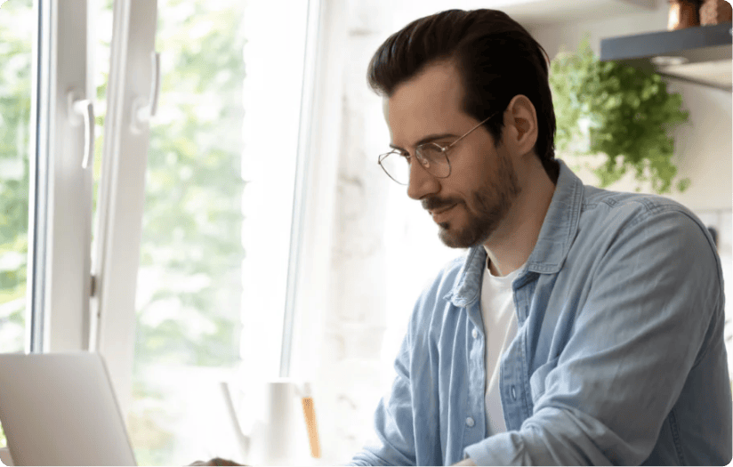 A side view image of a man working on his laptop.