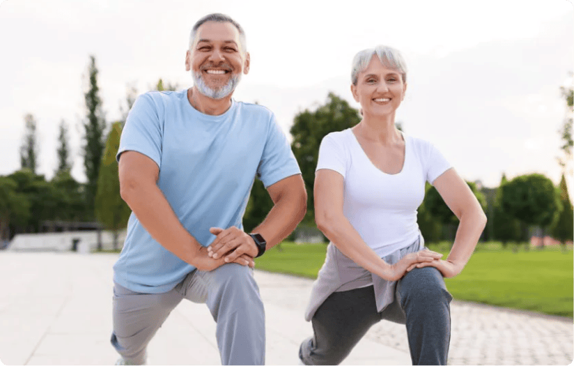 A smiling senior man and woman stretching on the street.