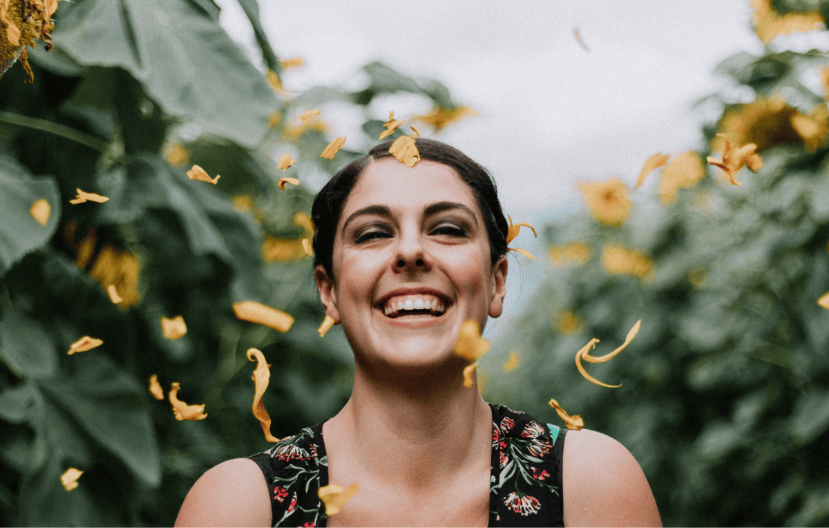 A woman is showing a happy smile while the yellow confetti is falling around her. 