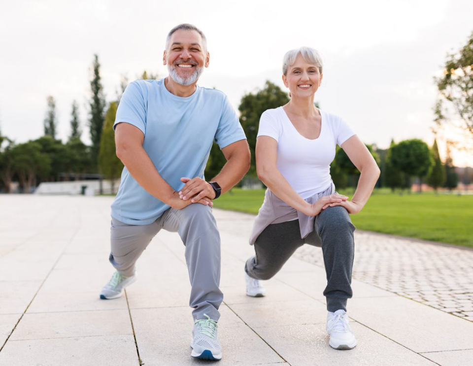 A smiling man and woman are stretching on the street.