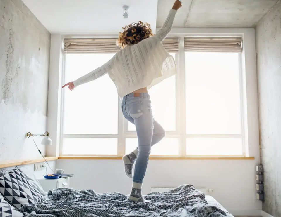 A woman is dancing on her bed.