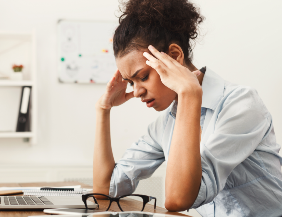 A woman is holding her head with a painful expression on her face.