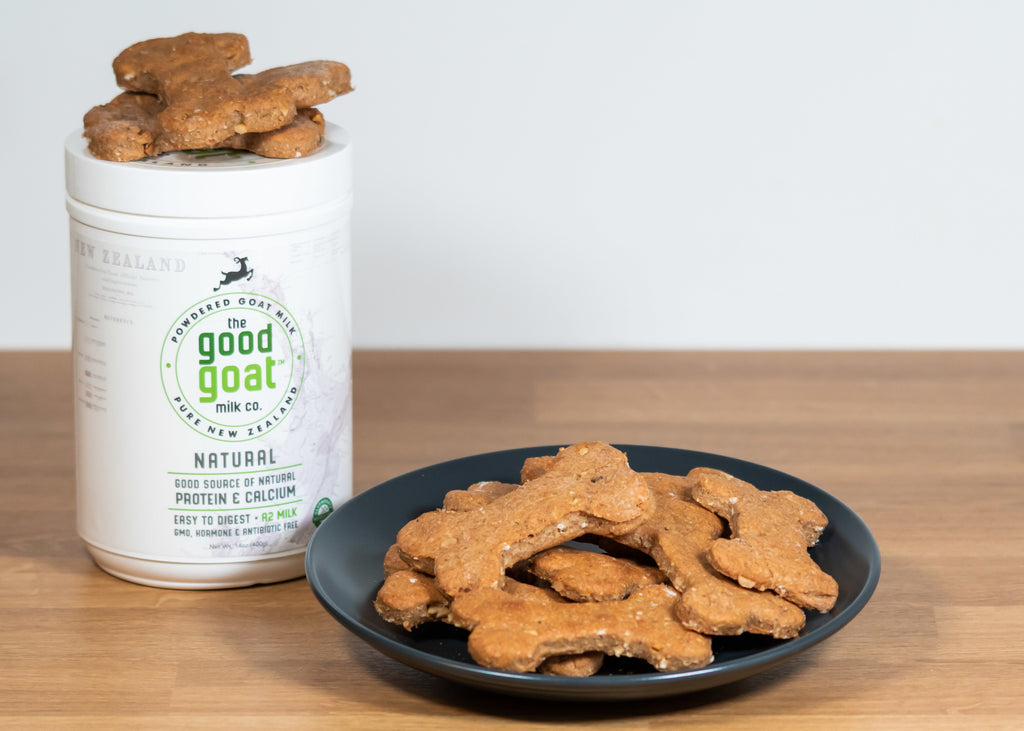 Container of Good Goat Milk Co powder and a black plate full of dogie biscuits