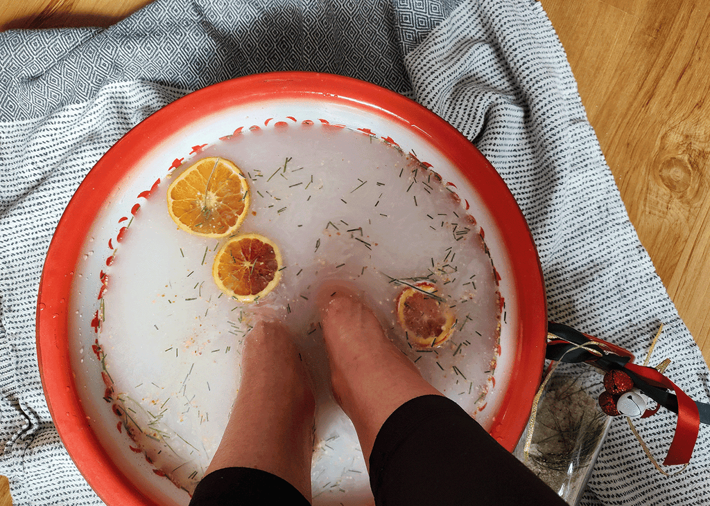 Soaking feet in metal bowl with red trim that is sitting on a Turkish towel. 