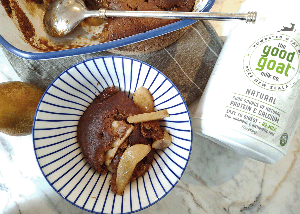 Pear bottom gingerbread in a blue and white bowl and a container of Good Goat Milk Co natural goat milk powder on a marble background.