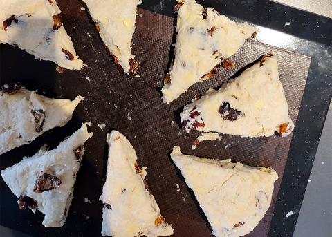 Date scones on baking tray separated with space to rise.