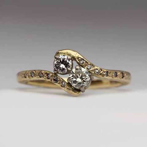 Yellow gold engagement ring with two diamonds held in an organic wave with small pave set diamonds in the shanks