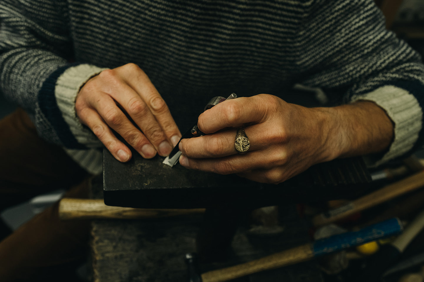 Sandcast Extra Texture Signet Ring worn on middle finger by jeweller in their workshop