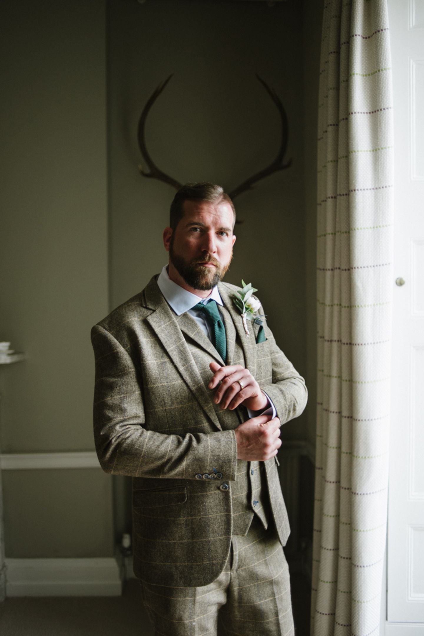 Groom portrait with stag horns, country house wedding