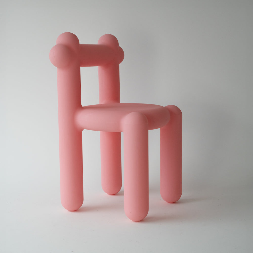 A minimalistic pink chair with stylized balloon animal design.