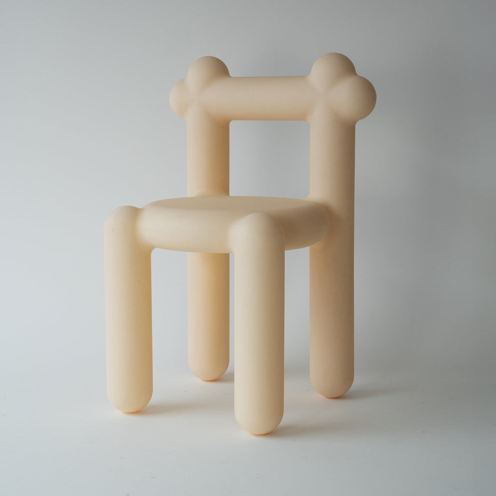 A simplistic, beige-colored chair with thick, rounded legs and armrests against a white background.