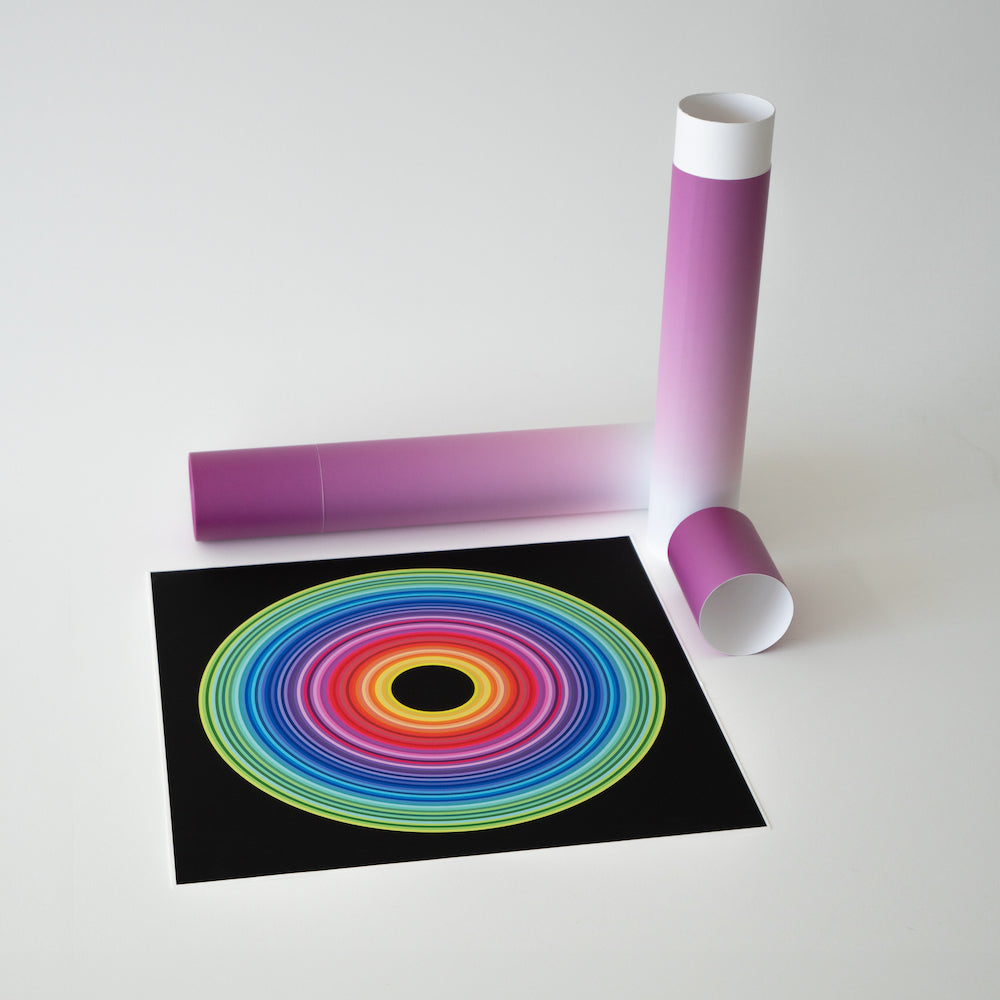 Colorful concentric circles print next to a purple poster tube on a white surface.
