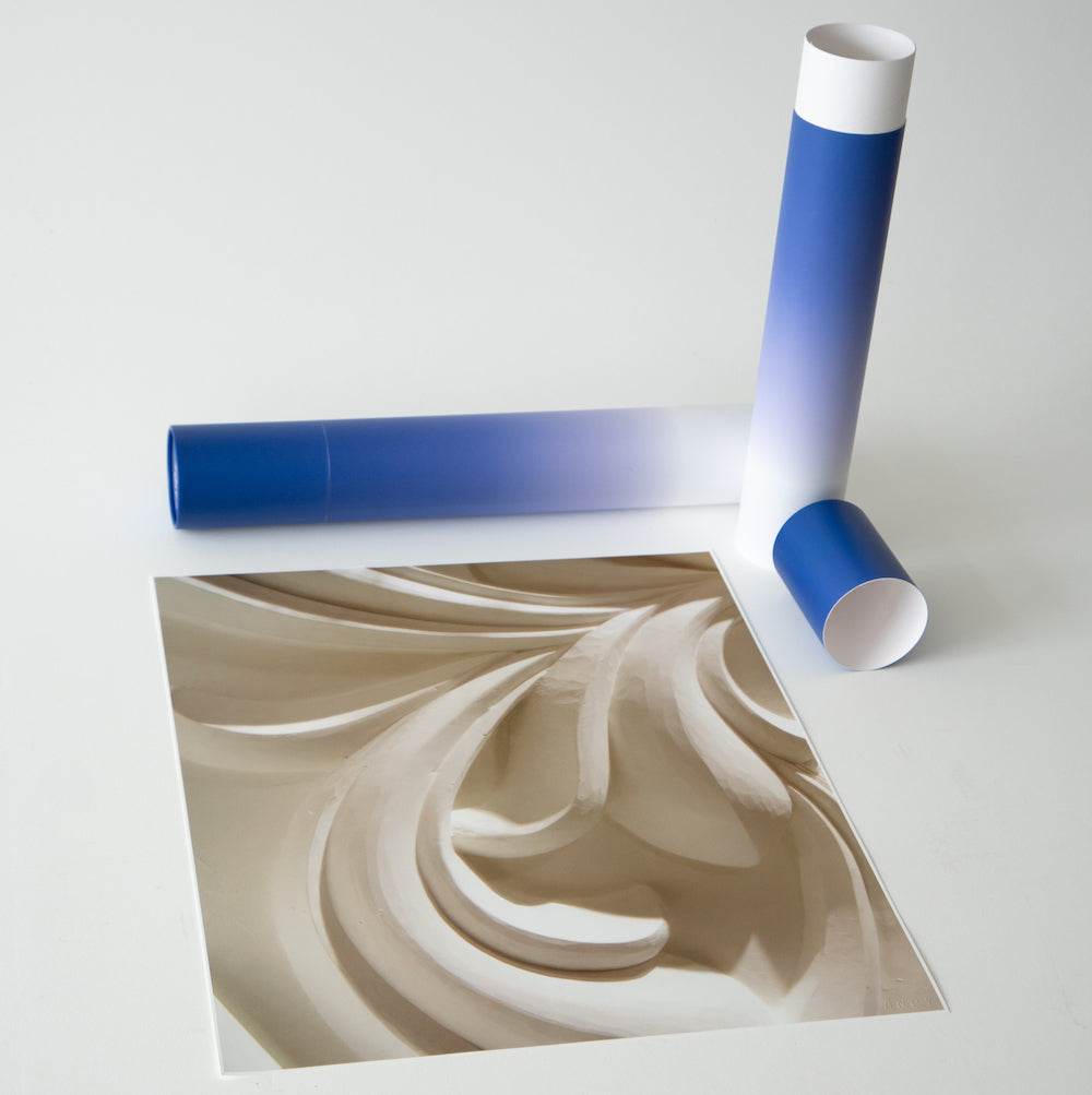 An abstract art print next to a partially unrolled blue poster tube.