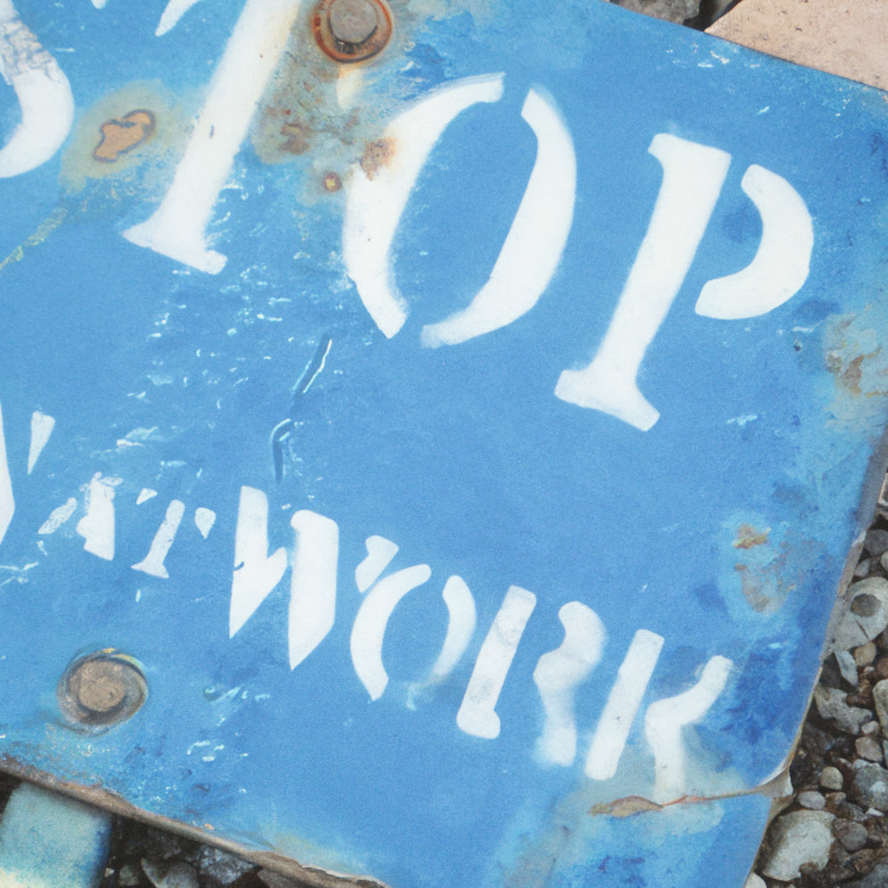 Close-up of a weathered blue 'STOP' sign with fading and rust.