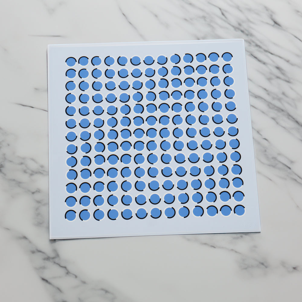 Blue circular stickers arranged in a grid pattern on a white sheet on a marble surface.