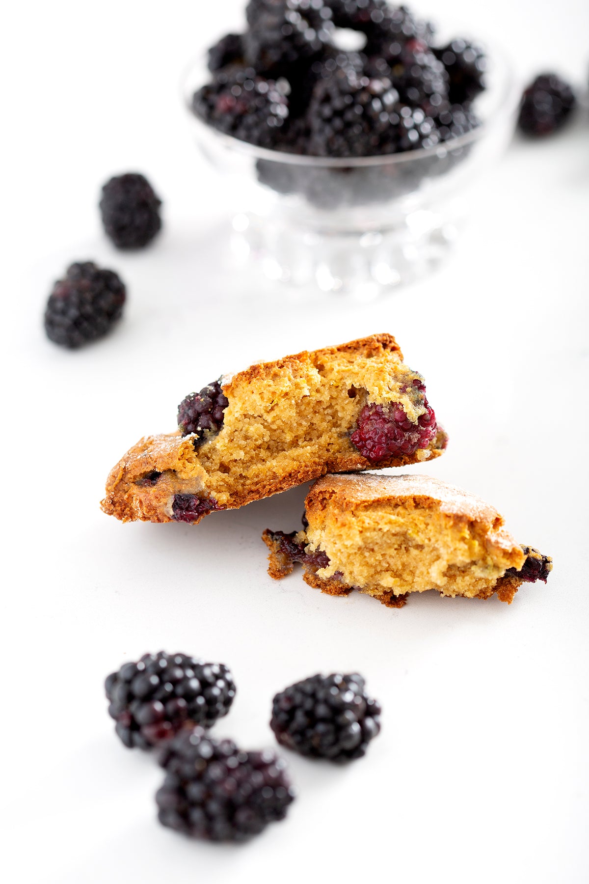 gluten free blackberry scone in half with blackberries on counter