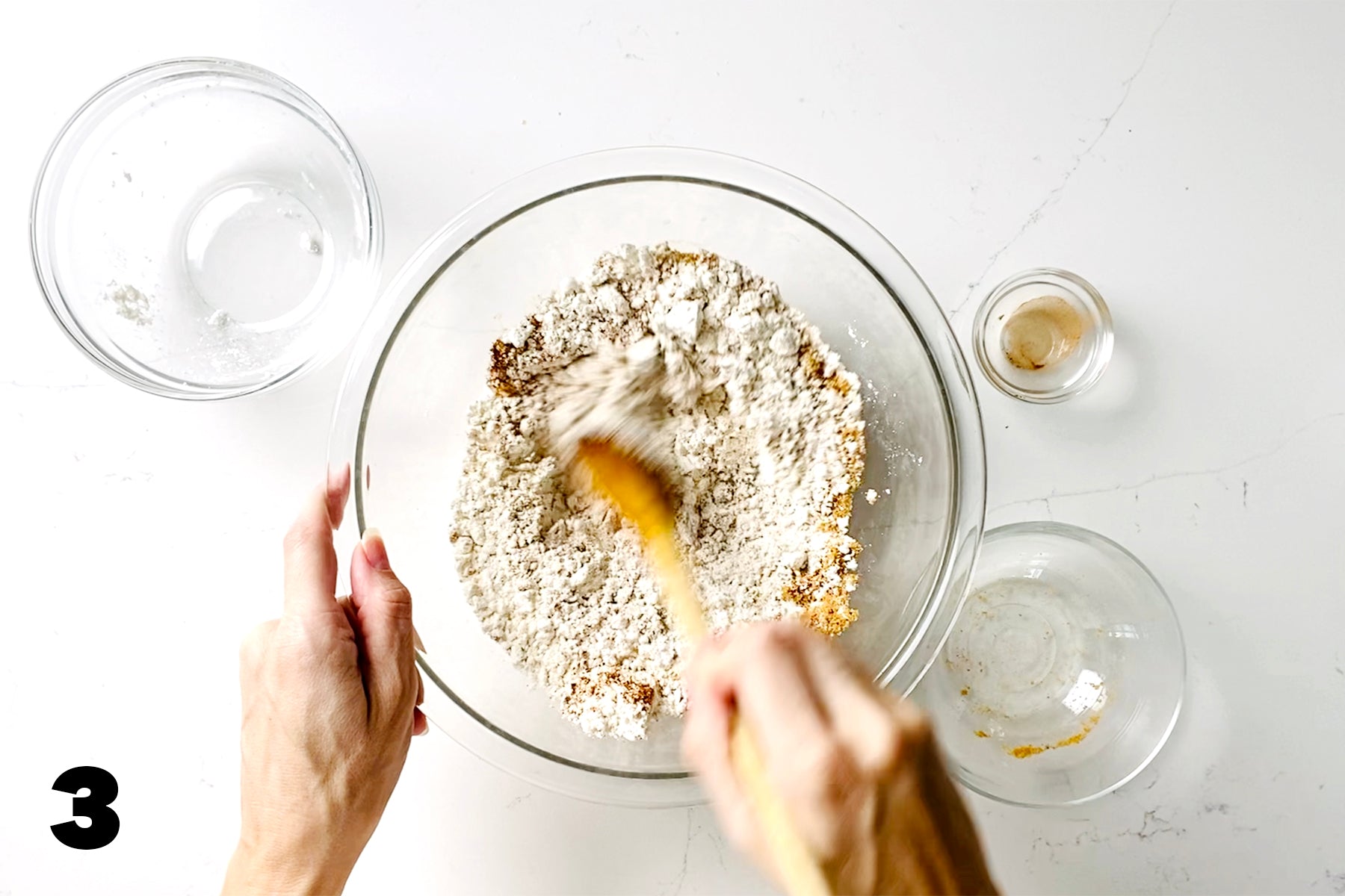 stirring flour in glass bowl with wooden spoon